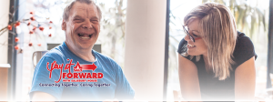 Man and woman sit at a table together smiling and laughing.