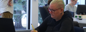 A woman sits at a desk writing